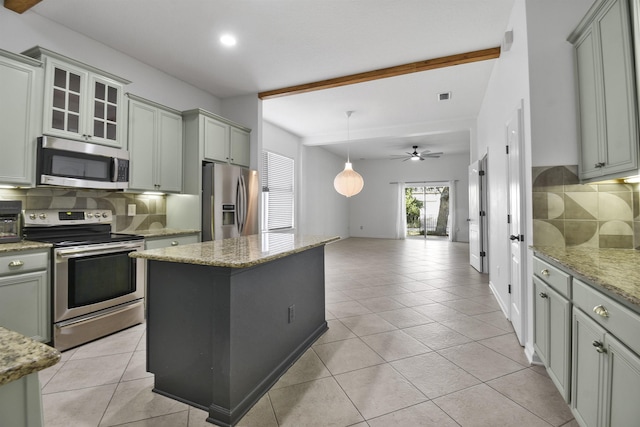 kitchen with gray cabinets, decorative backsplash, a kitchen island, and appliances with stainless steel finishes