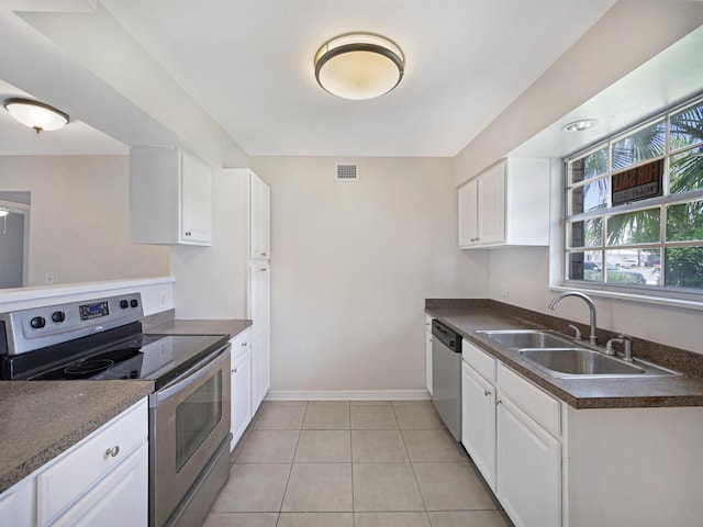 kitchen featuring white cabinetry, sink, light tile patterned flooring, and appliances with stainless steel finishes