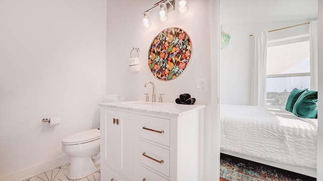 ensuite bathroom with toilet, baseboards, connected bathroom, and vanity