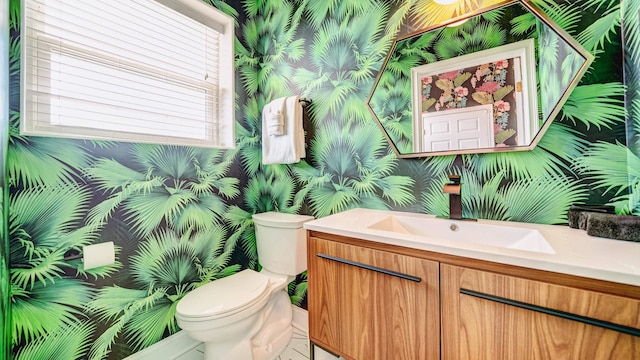 half bath with toilet, wallpapered walls, and vanity