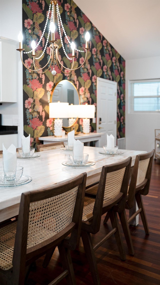 dining room featuring dark wood-type flooring, vaulted ceiling, and wallpapered walls