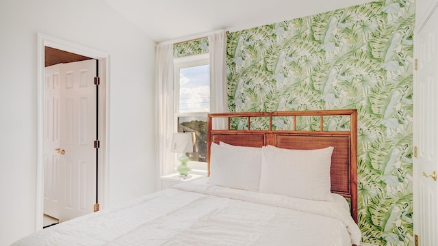 bedroom featuring vaulted ceiling and wallpapered walls