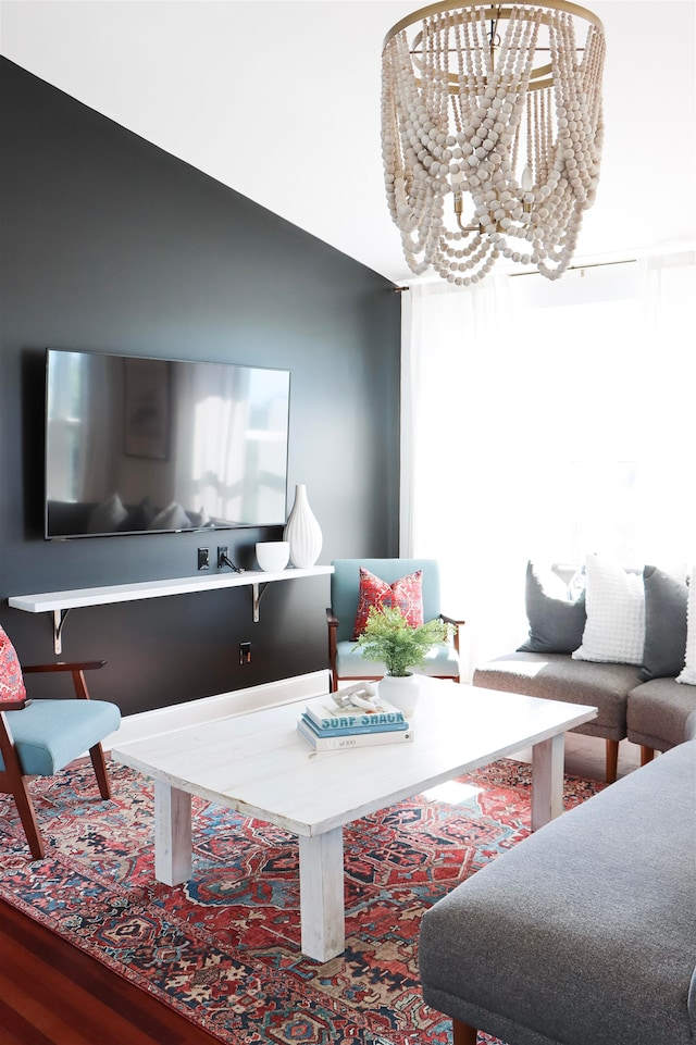 living area with lofted ceiling, a chandelier, and wood finished floors