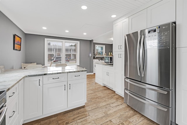 kitchen with washing machine and dryer, stainless steel appliances, white cabinetry, and light stone counters