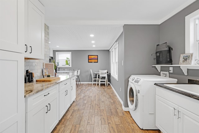 laundry area with washer and dryer, light wood-type flooring, sink, and ornamental molding