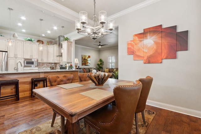 dining area with sink, wood-type flooring, ceiling fan with notable chandelier, and ornamental molding