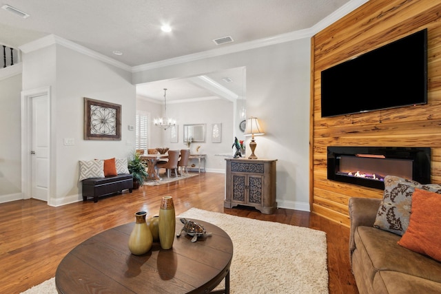 living room with hardwood / wood-style flooring, an inviting chandelier, and crown molding