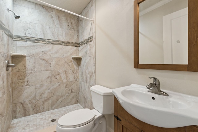 bathroom featuring vanity, toilet, crown molding, and a tile shower