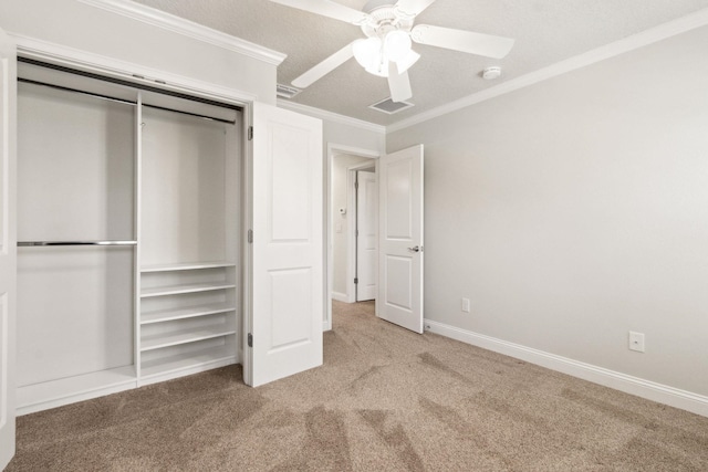 unfurnished bedroom featuring ceiling fan, ornamental molding, a textured ceiling, carpet floors, and a closet