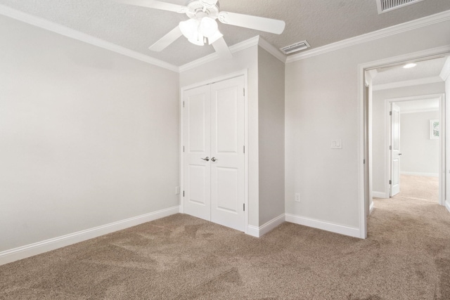 unfurnished bedroom with carpet flooring, ceiling fan, crown molding, a textured ceiling, and a closet