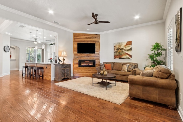 living room featuring ornamental molding, ceiling fan, sink, a fireplace, and hardwood / wood-style floors