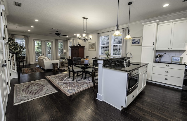 kitchen featuring visible vents, dark wood finished floors, ornamental molding, a sink, and stainless steel microwave