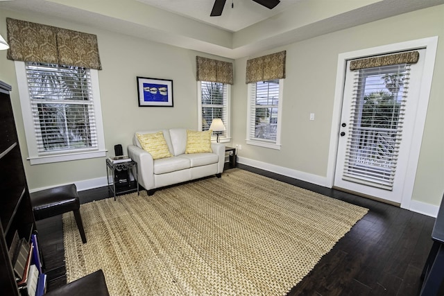 living area with ceiling fan, baseboards, and hardwood / wood-style floors