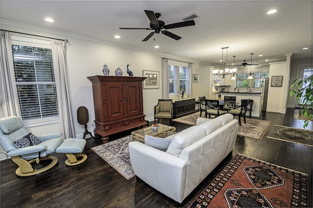 living area with recessed lighting, ornamental molding, ceiling fan with notable chandelier, and dark wood-style flooring