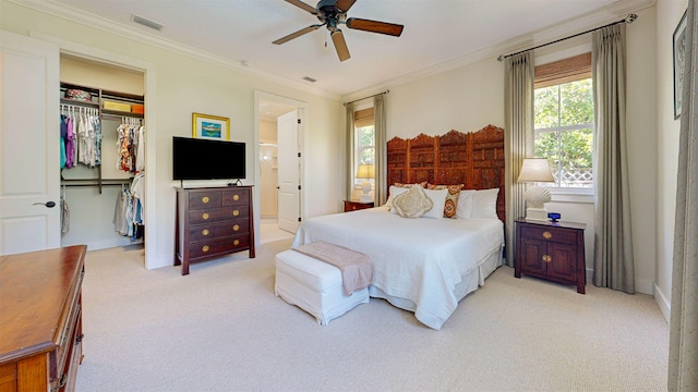 bedroom with a closet, light colored carpet, a spacious closet, and crown molding