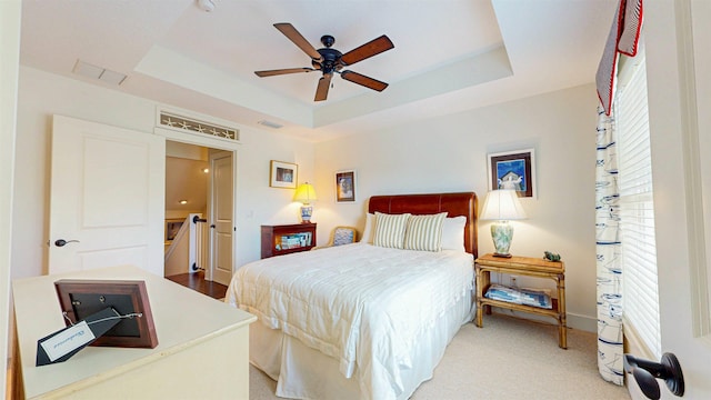 bedroom featuring visible vents, a ceiling fan, and a tray ceiling