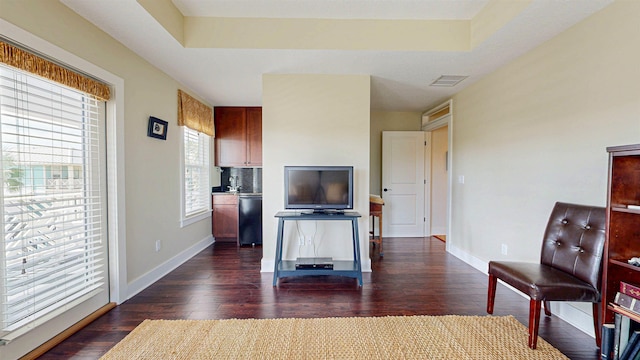 living area featuring visible vents, baseboards, dark wood-type flooring, and a raised ceiling