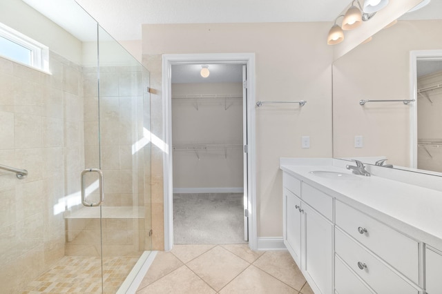 full bathroom with a stall shower, vanity, tile patterned floors, baseboards, and a walk in closet