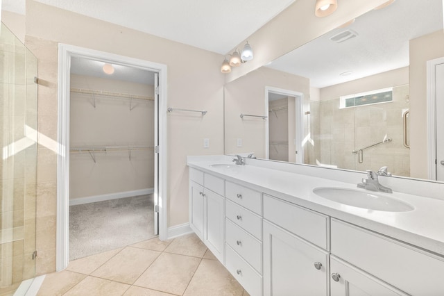 bathroom with a shower stall, double vanity, tile patterned flooring, a spacious closet, and baseboards