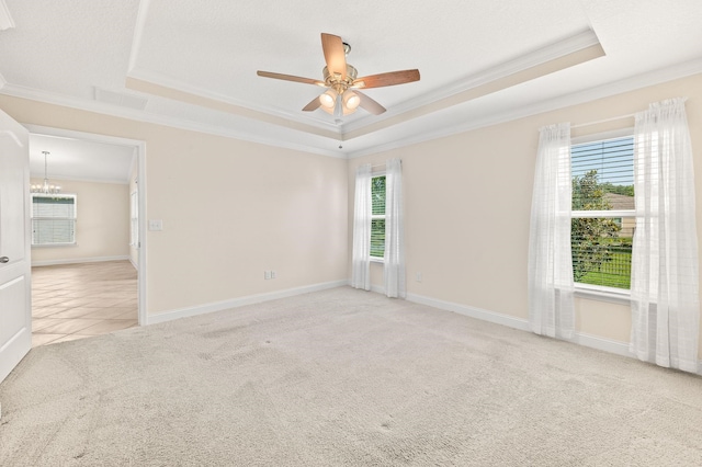 carpeted spare room featuring crown molding, a raised ceiling, healthy amount of natural light, a chandelier, and a ceiling fan