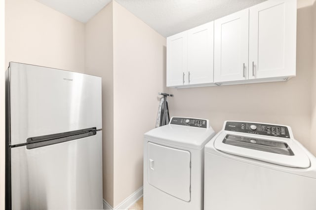 laundry area featuring cabinet space, washing machine and dryer, baseboards, and a textured ceiling