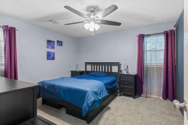 bedroom with a textured ceiling, carpet floors, and ceiling fan