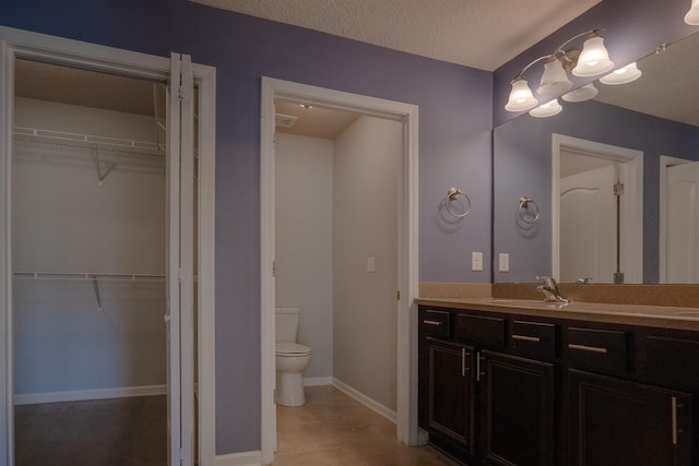 bathroom featuring a textured ceiling, tile patterned floors, vanity, and toilet