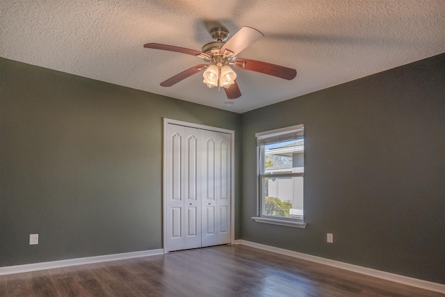 unfurnished bedroom with a closet, ceiling fan, a textured ceiling, and dark hardwood / wood-style floors