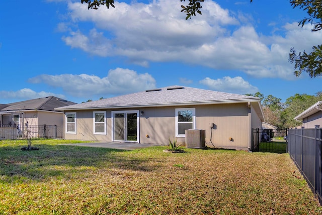 rear view of property with central AC and a lawn