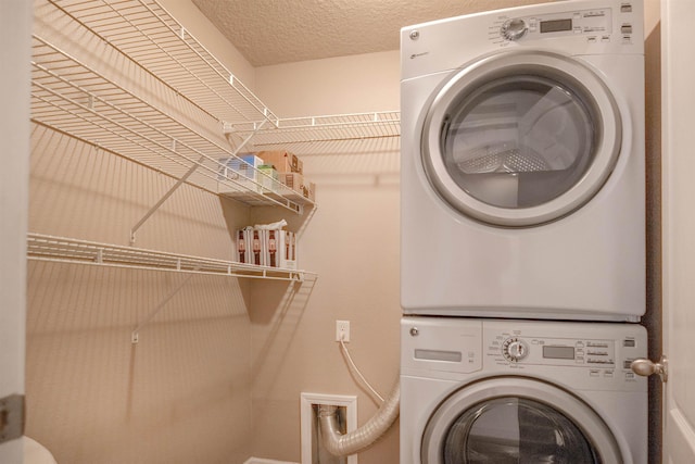 washroom with a textured ceiling and stacked washer / dryer