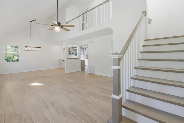 155 Drake Rd, Saint Augustine, FL 32086 - unfurnished living room with ceiling fan, stairs, a high ceiling, light wood-type flooring, and baseboards