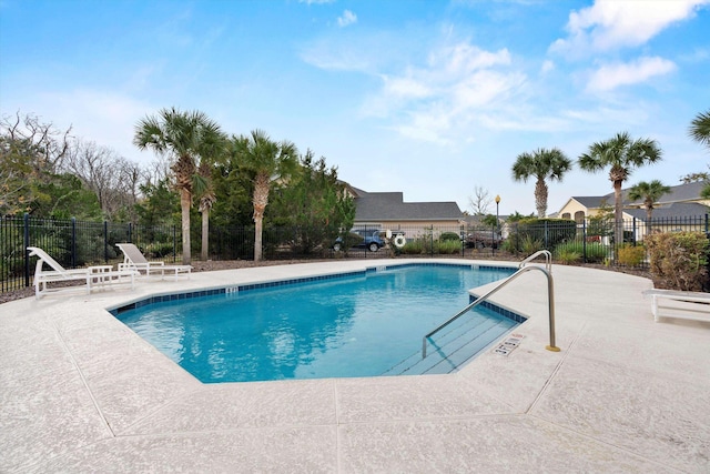 community pool with a patio area and fence