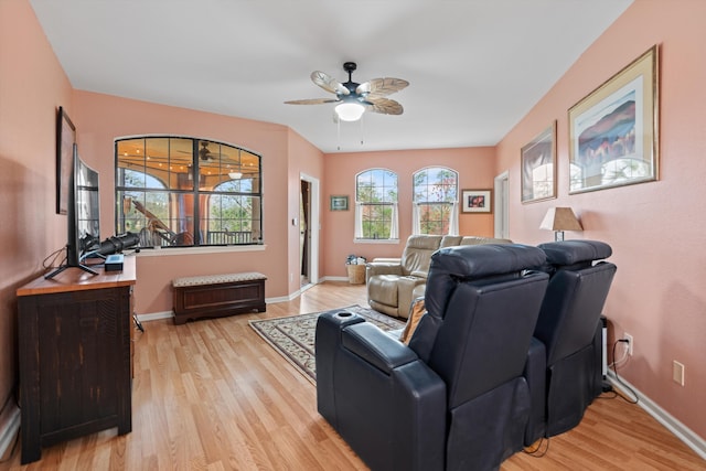 living room with light wood finished floors, a ceiling fan, and baseboards