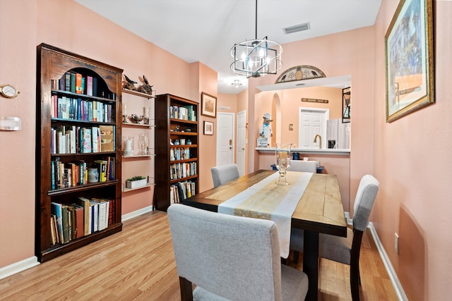 dining space with visible vents, baseboards, light wood-style flooring, and an inviting chandelier