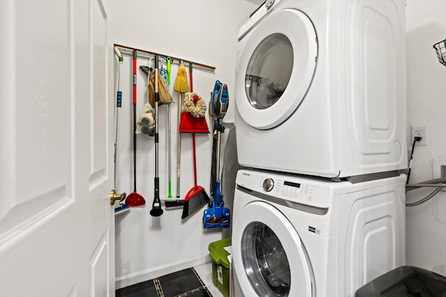 washroom featuring stacked washer and dryer, laundry area, and baseboards