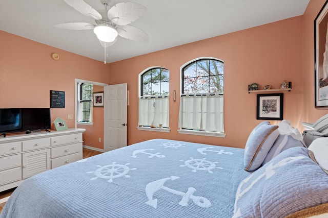 bedroom featuring multiple windows, wood finished floors, and a ceiling fan