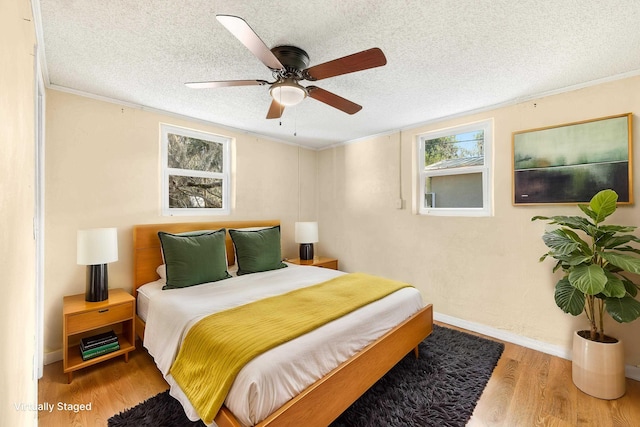 bedroom featuring a textured ceiling, ceiling fan, wood finished floors, baseboards, and ornamental molding