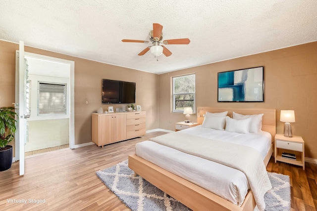 bedroom featuring a textured ceiling, ceiling fan, light wood-type flooring, and baseboards