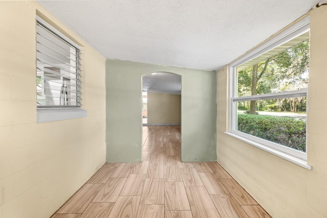 unfurnished room featuring arched walkways and a textured ceiling