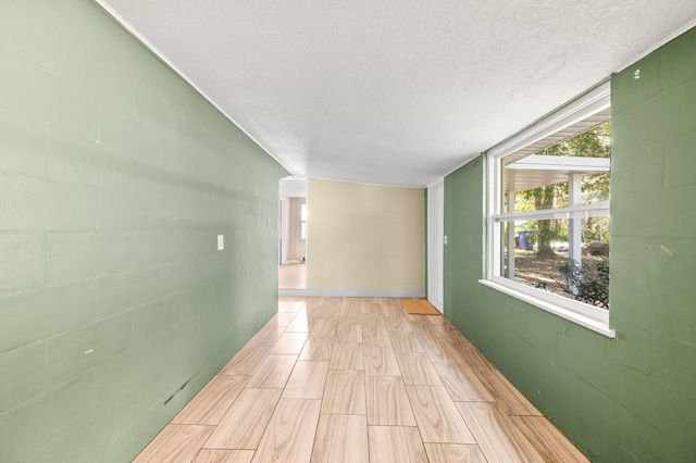 corridor with concrete block wall and a textured ceiling