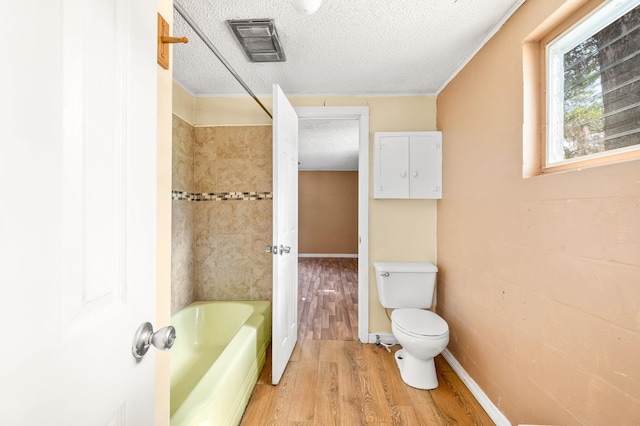 bathroom with bathing tub / shower combination, visible vents, toilet, a textured ceiling, and wood finished floors