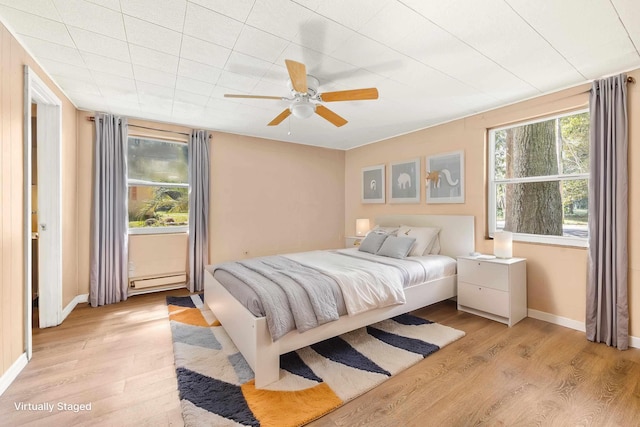 bedroom featuring baseboards, ceiling fan, light wood-style flooring, and baseboard heating