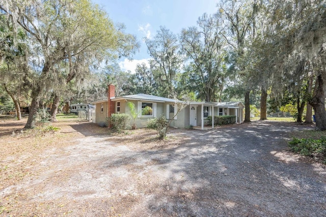 single story home featuring driveway and a chimney