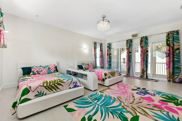 bedroom with a chandelier, access to outside, wood finished floors, and baseboards