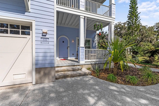 view of exterior entry featuring a garage and covered porch