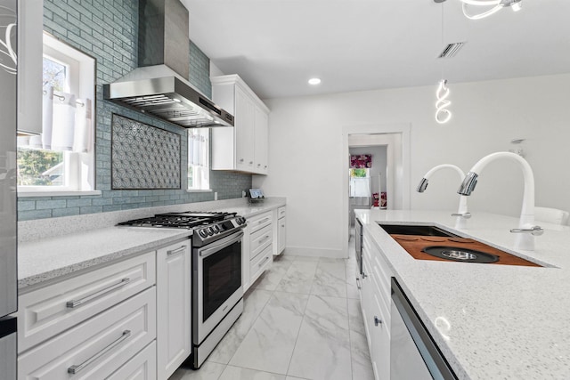 kitchen with stainless steel appliances, a sink, marble finish floor, backsplash, and wall chimney exhaust hood