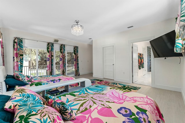 bedroom with visible vents, an inviting chandelier, wood finished floors, access to outside, and baseboards