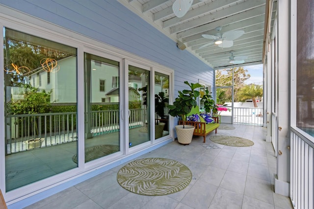 sunroom / solarium with beam ceiling and a ceiling fan