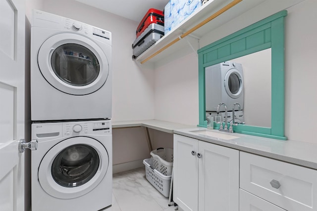 laundry room with stacked washer and clothes dryer, cabinet space, a sink, and marble finish floor