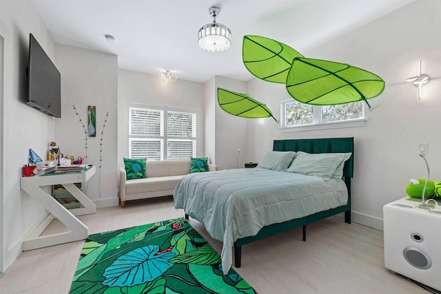 bedroom with multiple windows, baseboards, and wood finished floors